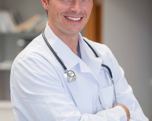 Smiling doctor with arms crossed in hospital reception Smiling doctor with arms crossed in hospital reception